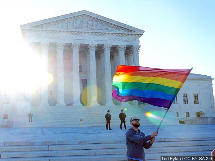 Man holding pride flag in front of Supreme court.