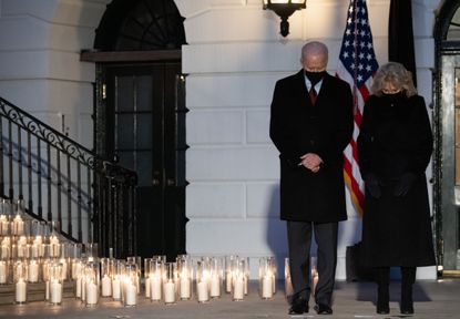President and First Lady Biden stand on the South Portico of the White House during a candle light ceremony for those lost to COVID-19. 