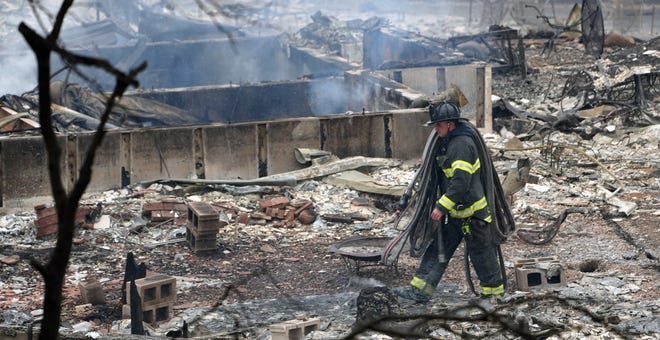 A firefighter walks through the remains of a burned home in Louisville, Colorado.