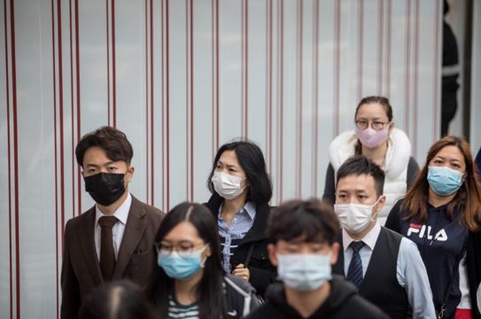 Hong Kong officials leaving an airport with masks on. 