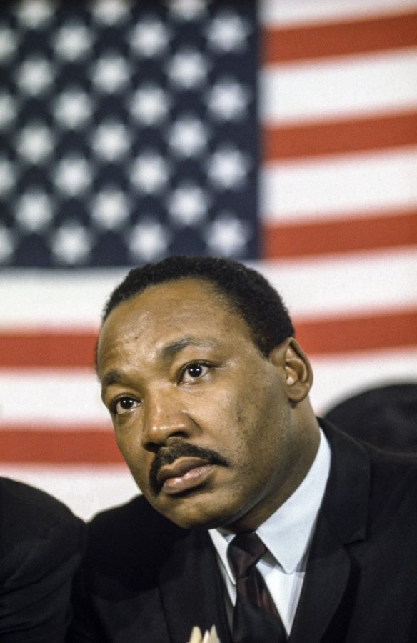 Martin Luther King Jr standing behind the United States Flag.