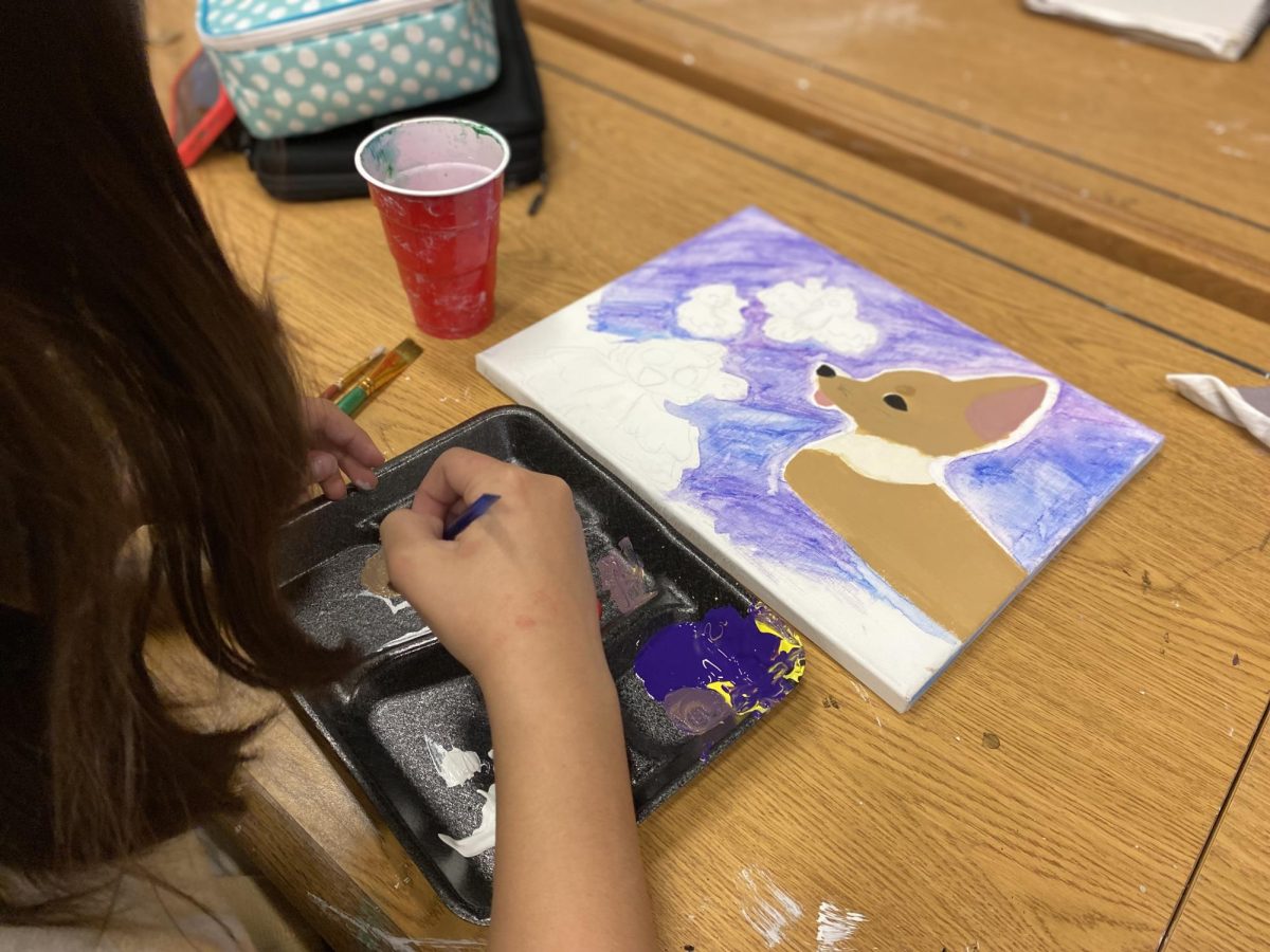 Picture of a middle school student working on a canvas painting.