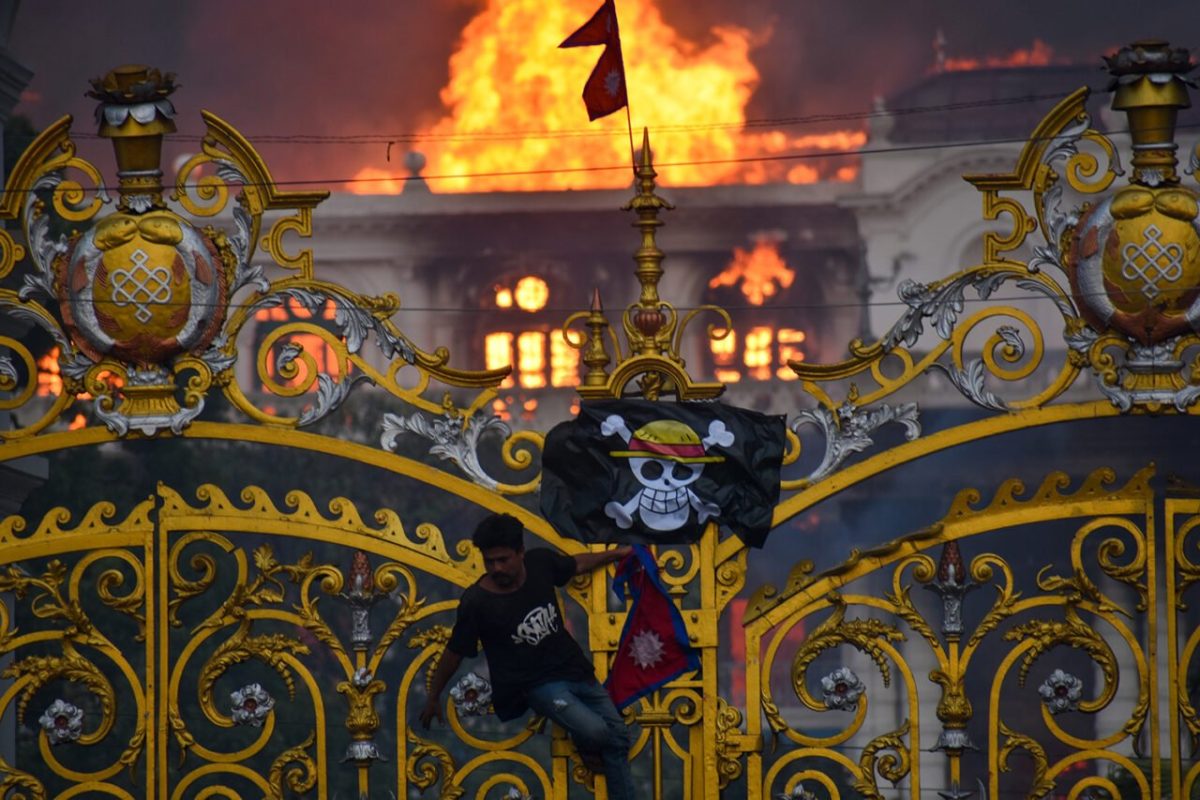 A One Piece flag hangs on the gates of the Singha Durbar palace in Kathmandu, Nepal on September 9 as smoke and flames rise from the building.