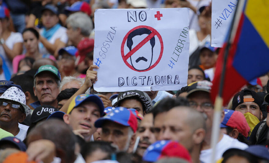A man holds a sign with an image representing President Nicolas Maduro and a message that reads in Spanish: "No more dictatorship," during an anti-government rally led by opposition politician Juan Guaido, in Caracas, Venezuela, Saturday, Nov. 16, 2019. Guaido called nationwide demonstrations to re-ignite a campaign against President Nicolas Maduro launched in January that has lost steam in recent months. (AP Photo/Ariana Cubillos)