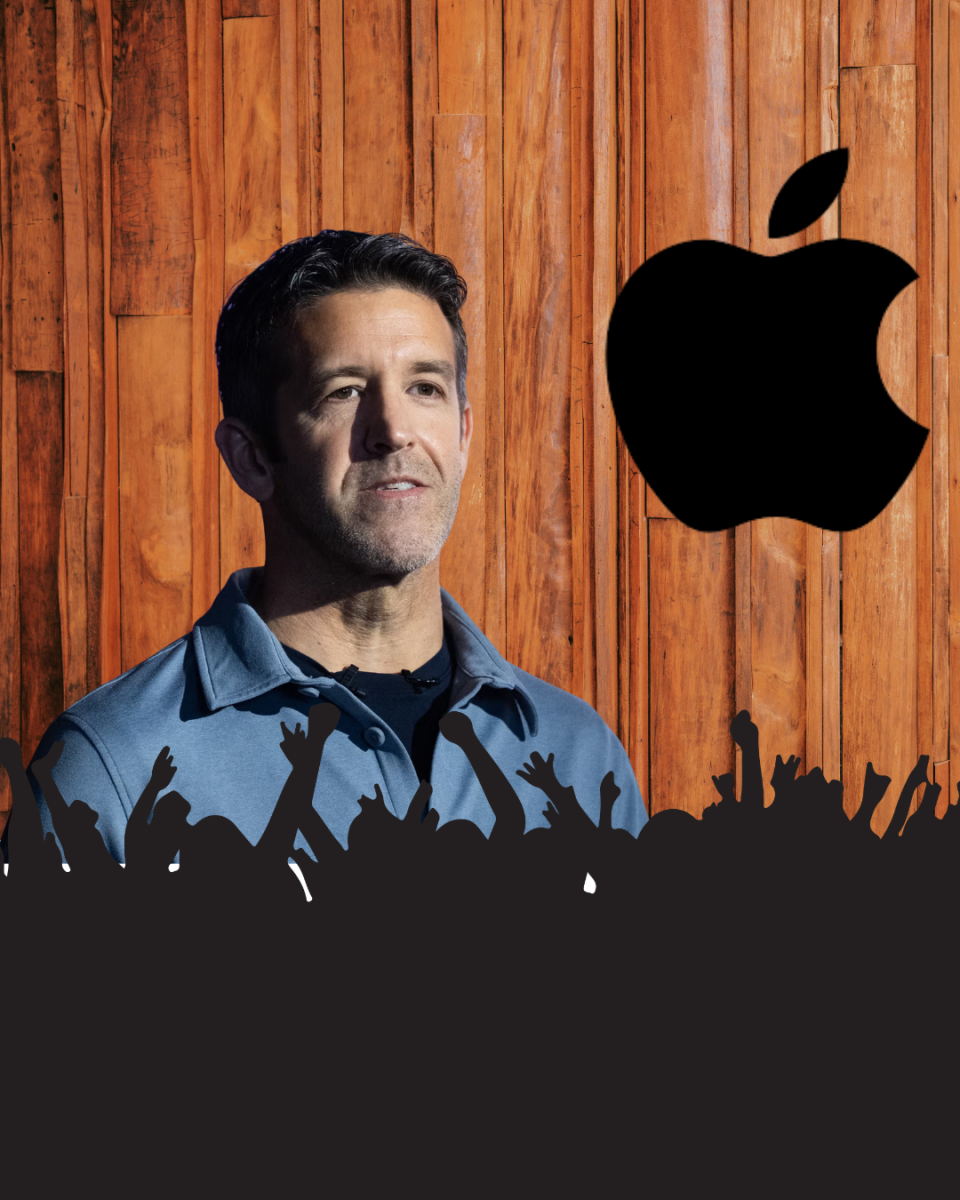 John Ternus in front of a crowd with the Apple logo beside him